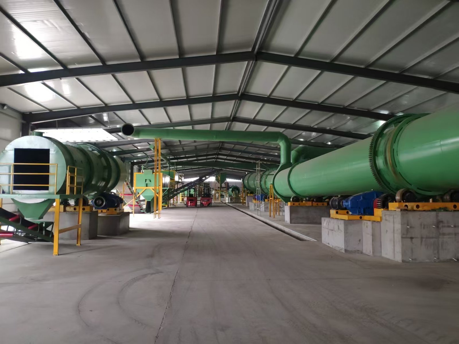 Jinyuelong organic fertilizer production line for round granules, with rotary drums and belt conveyors inside a factory
